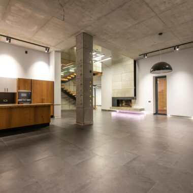 Spacious modern kitchen with minimalist design, concrete ceiling, and open layout.