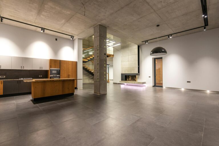 Spacious modern kitchen with minimalist design, concrete ceiling, and open layout.